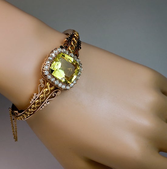 This late 19th century Russian bracelet is handcrafted in polished rose and matte yellow gold. It is set with a cushion cut golden beryl - heliodor of a beautiful yellow green color (approximate weight 15.5 Ct), surrounded by a row of old cut