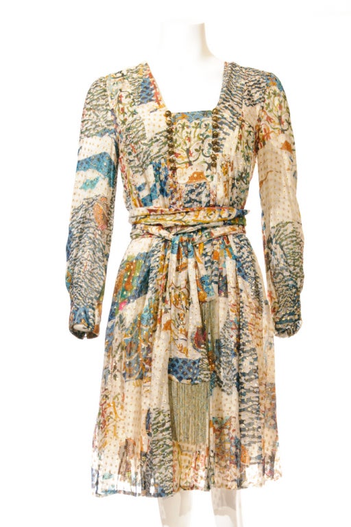 A multi-color long-sleeved dress in printed silk with metallic specks.  It's adorned  with two rows of gold buttons at front and button-fastening cuffs. The matching sash with metallic fringes can let you create your own curve easily.