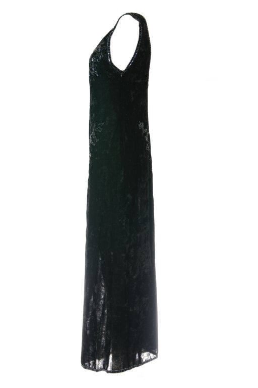 A V-neck black silk-velveteen ankle-length dress adorned with black and silver beads in both the front and the back. It has a lightness in movement and shimmer, feminine and timeless.