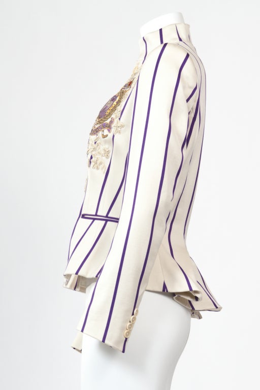 A classic cream and purple pin-striped cotton peplum jacket from Ralph Laurent Purple Label Collection.  It is embroidered with flowers and a gold and purple threaded badge.  It has a stand up collar with front button closure, button cuffs and two