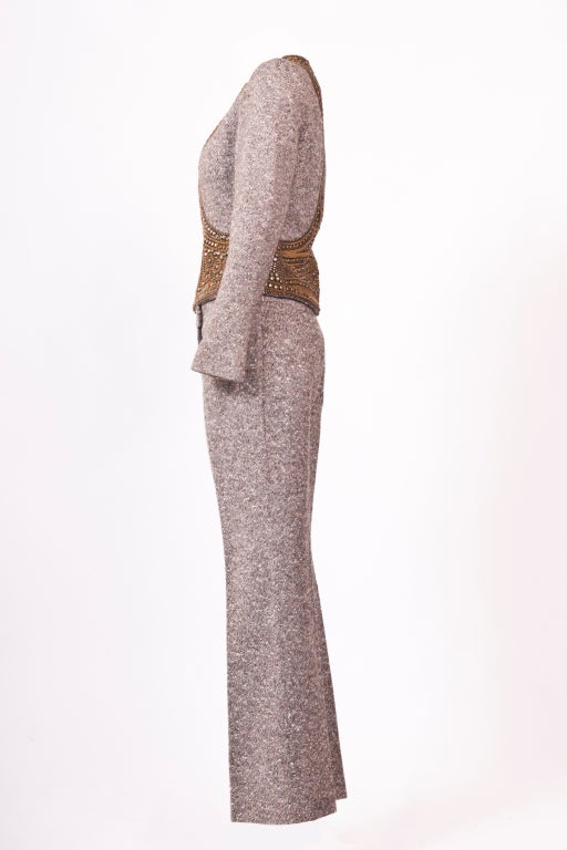 A very unique and gorgeous collarless embellished jacket and wool tweed pants suit from Alexander McQueen.  Zip fastening on front with zip fastening cuffs.  Wool tweed straight-leg pants with hook and zip fastening at waist.  