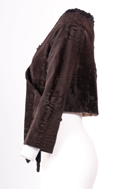 A Prada brown collarless broadtail lamb fur short jacket.  Meticulously embellished with beads around the neckline.  Concealed hook fastenings at front.