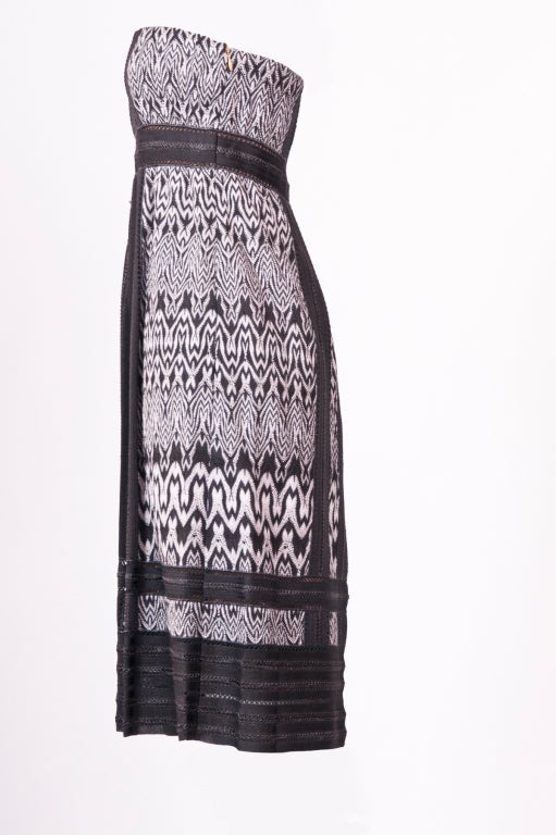 A  strapless black and white Missoni crochet dress with dark grey panels. The internal boned structure holds and supports the neckline. Two concealed side pockets.  Zip fastenings at side. Fully lined.