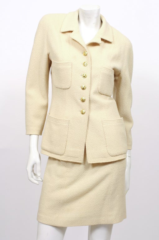 Chanel Boucle Cream two piece suit consisting of a jacket and skirt. Both with silk lining and the Chanel logo. Jacket has gold toned Chanel-logo buttons. Excellent condition.

Jacket:
34