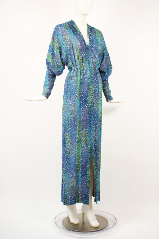 Gorgeous 1970s Rhinestone Studded Blue, Purple and Green Dress. Slit in front with snap closures. The fabric looks almost like a watercolor print. Dolman sleeves with zipper closures at wrist. Excellent condition except for a couple of pulls in