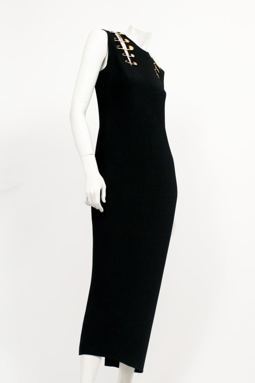 Iconic and very rare safety pin dress from the Spring 1994 collection that launched Elizabeth Hurley's career. It is form fitting with small to large gold safety pins holding up the front and back of the dress. Several of the safety pins have