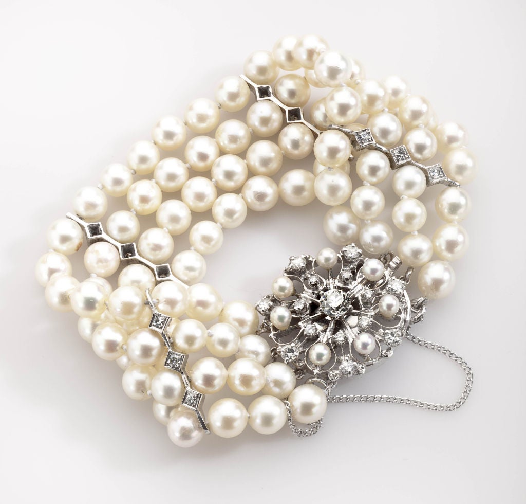Four strands of creamy white cultured pearls with pink overtones, approximately 8 mm in size, are strung in knotted strands with four spacers, each holding three full cut small diamonds. The pearls are blemish free and beautifully color matched. The