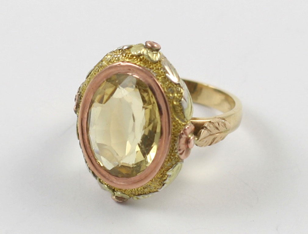 Description: Pink gold frames a faceted lemon citrine and this touch of an accent color enhances the stone and the superb engraving surrounding it. The gold is both hammered and embossed. Raised flowers are appliqued on the perimeter of the face as