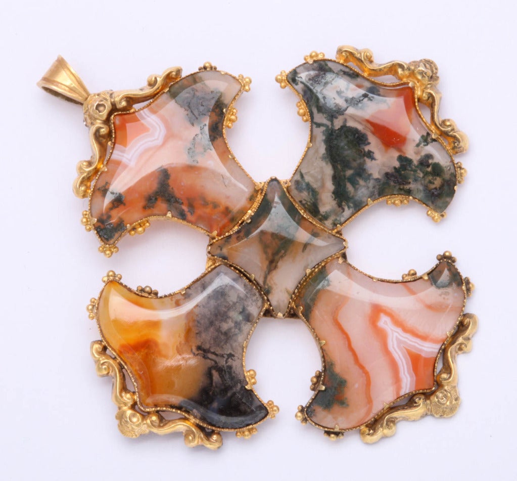 Translucent agate stones display a natural panorama on this sculptured maltese cross. The agates are set in high karat gold repousee trim. Hold this jewel to the light and be astonished to witness what nature and the hand of man have made. The