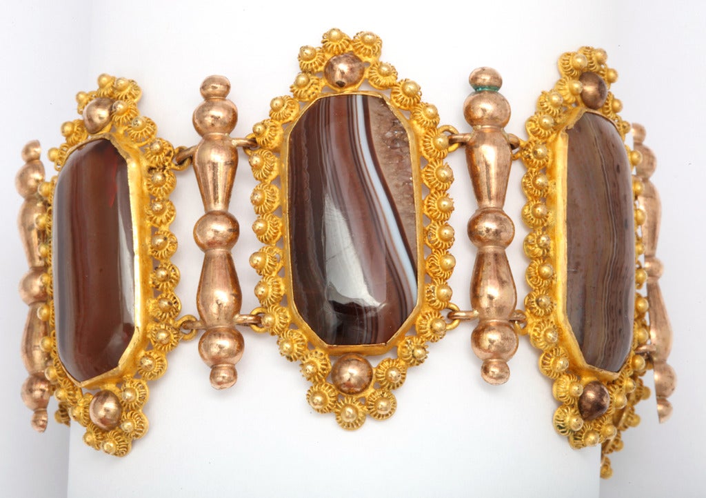 There are times when man can enhance nature as he did when placing naturalbanded agates from various parts of the earth with the golden metal created by Christopher Pinchbeck. Genuine Pinchbeck Rosettes frame earth toned agates that are separated by