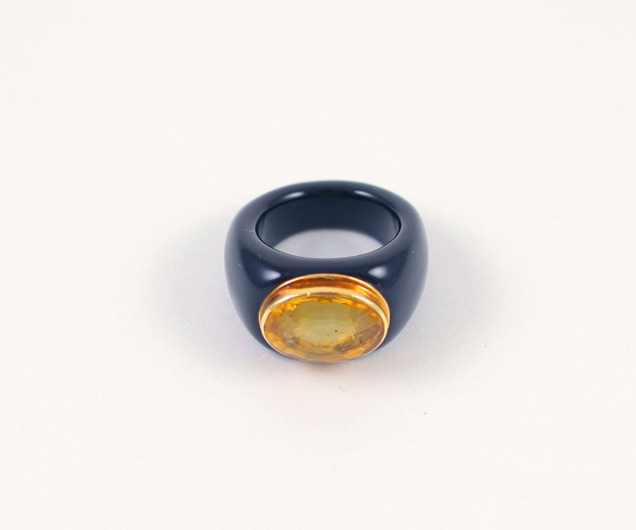 Black resin with a honey-lemon citrine make a fashion statement in this citrine set ring fashioned in the mid 20th century. The wider length of the oval citrine covers the finger top. The stone is set in 14 kt gold and raised above the bit of black