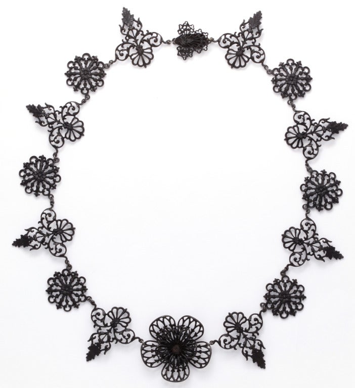 A three dimensional flower is at the center of the neckline in this garland of iron. Alternate links are rosettes, and vines. Berlin Iron jewelry is a prized possession and has been since early 1800. It is light on the body, delicate in appearance,