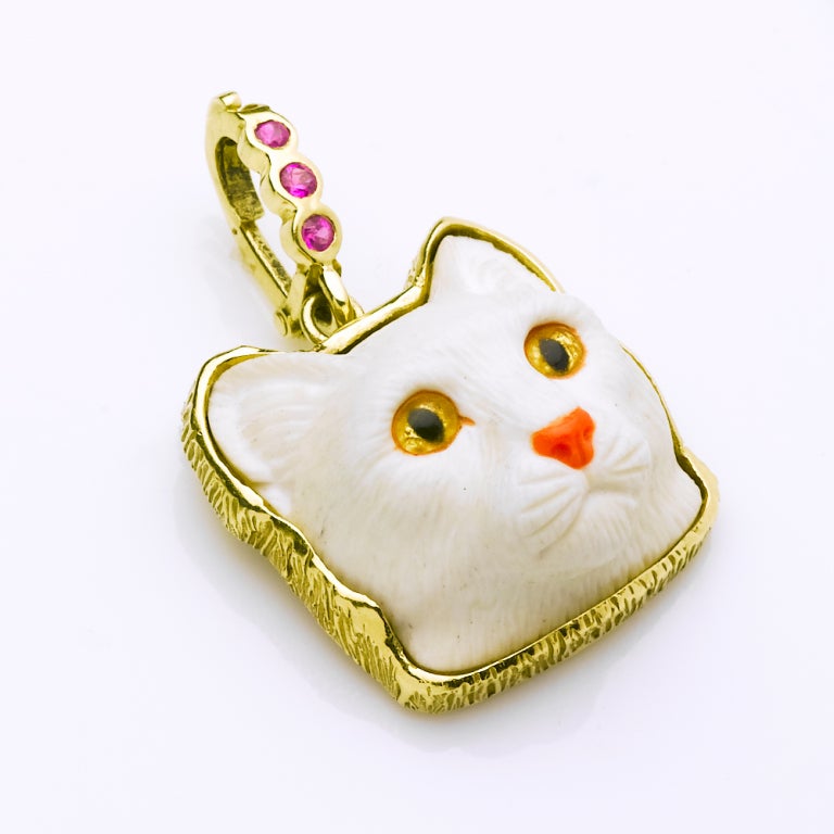 For cat lovers here is a beautifully hand carved cocholong cat's head pendant with crystal eyes set in an 18 karat gold frame with a detachable .30ct pink sapphire bail to hang from your necklace. 24x24x14mm stone size. Created by Master