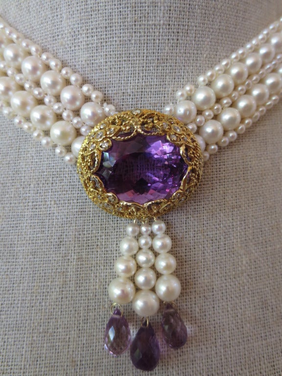 This unique centerpiece is reminiscent of the high quality craftsmanship of a bygone era. Large oval shaped faceted amethyst is set within a one of a kind, handmade, 14k gold floral filigree frame detailed with diamonds. The centerpiece is