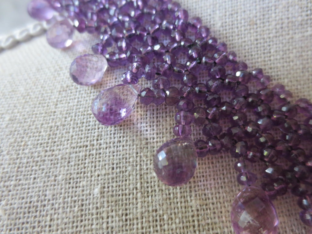 This necklace is intricately hand woven using 2-3 mm amethyst faceted beads.  Necklace is tapered in design to fit snugly along the curve of the neckline. Graduated amethyst briolettes hang from the lace work design, creating a beautiful and unique