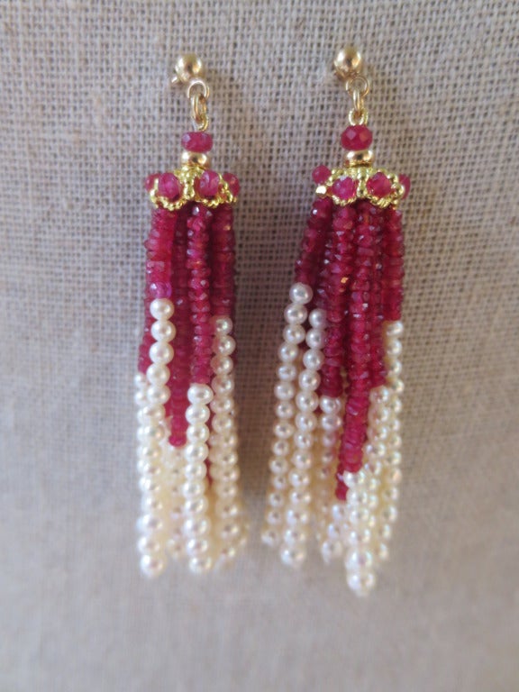 These elegant pearl and ruby faceted beaded tassel earrings are completed with 14k yellow gold studs. The brilliant red faceted ruby beads hang in gorgeous tassels with glowing pearls, creating a luxurious feel to the earrings. The strands hang from