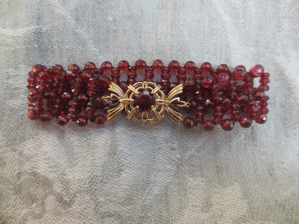 The woven and multi-stranded faceted garnet beaded bracelet is made with rich red faceted 3 mm garnet beads and a 14k yellow gold clasp. The bracelet is handwoven with a durable silk blend thread. Its clasp is made of 14k yellow gold and a beautiful