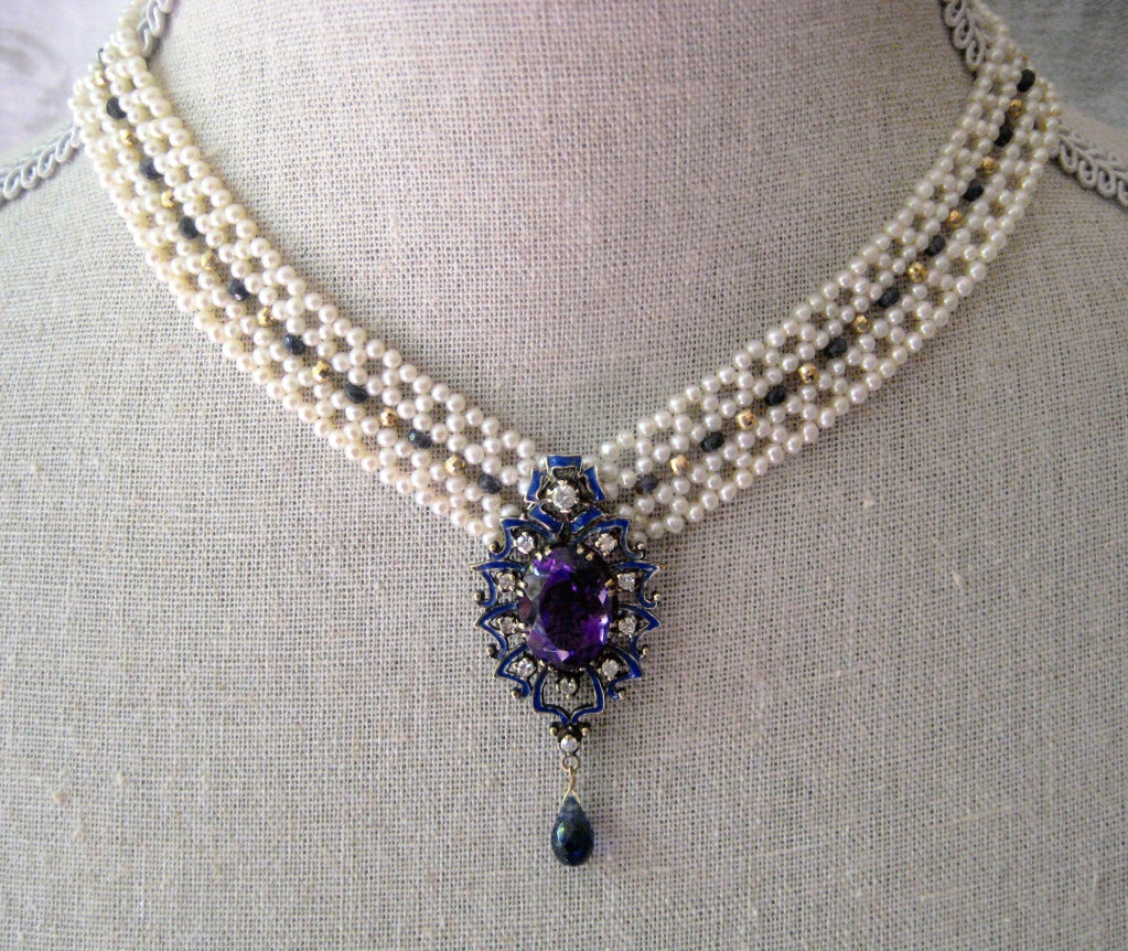 This unique centerpiece is reminiscent of the high quality craftsmanship of a bygone era. Made of blue enamel, diamonds and amethyst, and an iolite briolette, the centerpiece is complemented by an intricately woven pearl necklace accented with