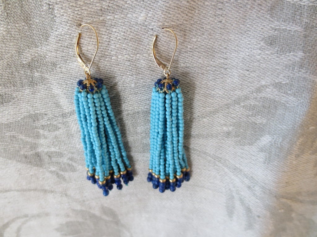 These tassel earrings are made of tiny turquoise and lapis beads measuring approximately 1mm each. Each strand is detailed with a 14k gold rondelle between the turquoise and the lapis lazuli beads. The tassels hang from a 14k gold filigree cap.