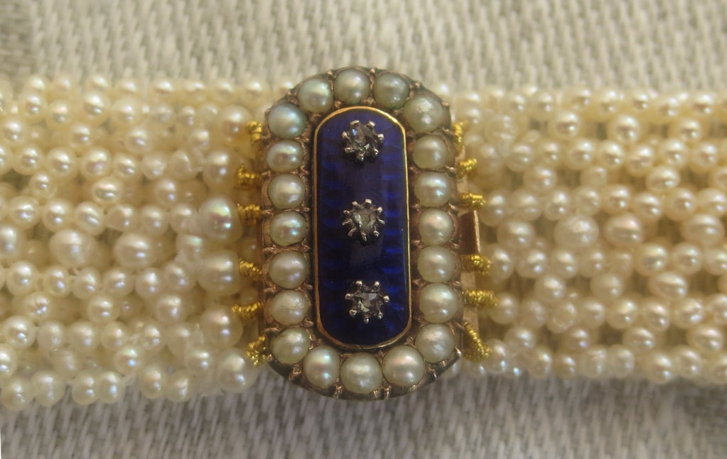 Antique 19th century blue enamel clasp has been re-imagined on this unique one of a kind seed pearl bracelet. The clasp is in excellent condition with original natural pearls and diamonds. Bracelet is hand woven with antique and natural seed pearls,