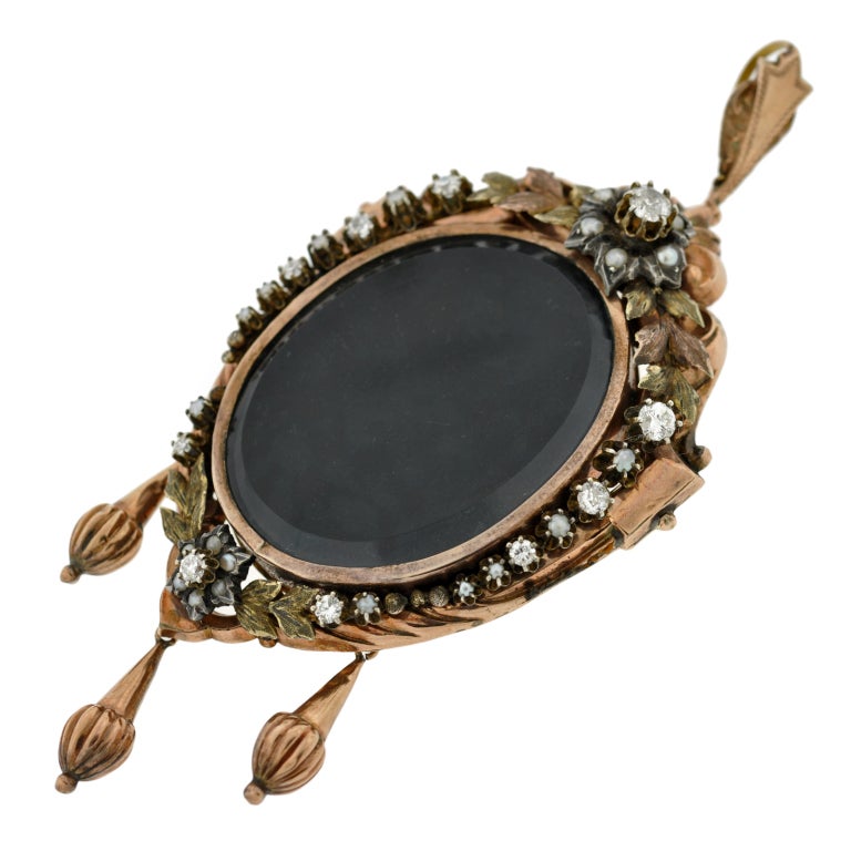 A fabulous and unique locket from the Victorian (ca1880) era! This large piece has a shield-like shape and is made of 15kt rose gold. In the center is an oval shaped locket face which has a crystal face. The locket is framed by a gorgeous wreath