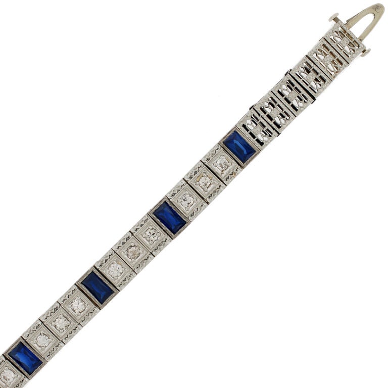 A simply stunning diamond and sapphire line bracelet from the Art Deco (ca1930) era! This gorgeous bracelet is made of 14kt white gold and features 7 French cut synthetic sapphire stones which alternate with rows of 3 old Mine Cut diamonds. The