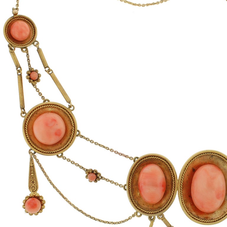 An exquisite coral festoon necklace from the Victorian (ca1800) era! This stunning necklace is made of 18kt yellow gold and gorgeous coral cabochons. The necklace features 8 gold concave discs, which vary in size and are detailed with a twisted gold