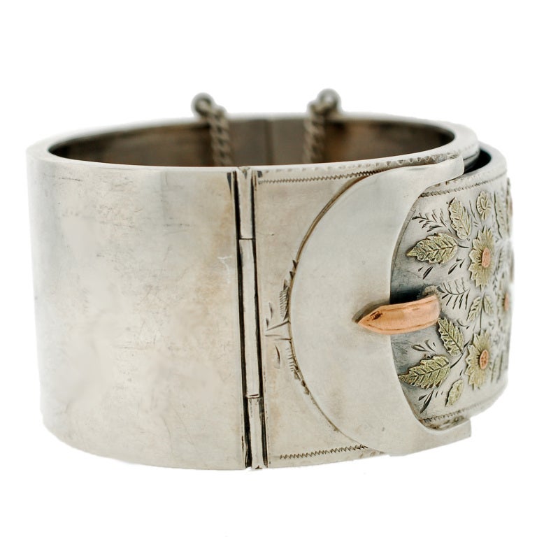 An absolutely fabulous and unusual sterling bracelet from the Victorian (ca1880) era! This gorgeous sterling silver piece is particularly wide and has a mixed metals floral design across the surface. Made to look like a buckle, the design has a