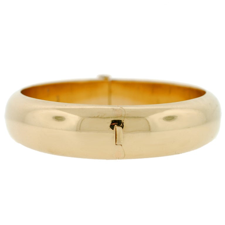A fabulous Estate gold bangle bracelet from the Tiffany & Co. collection! This simple yet fashionable bracelet is made of vibrant 14kt yellow gold, and is smooth all the way around the surface. The bracelet is hinged and opens and closes at a small