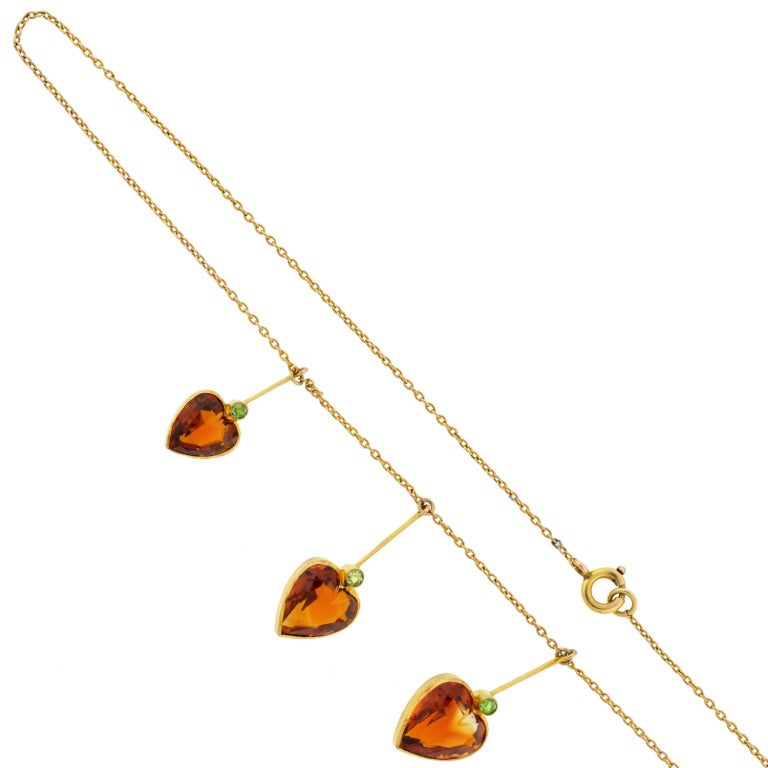 A beautiful festoon citrine necklace from the Art Nouveau (ca1900) era! Made of vibrant 9kt yellow gold, the delicate chain is adorned with five dangling hearts, giving the piece a romantic and feminine look. The hearts, which hang from a thin gold