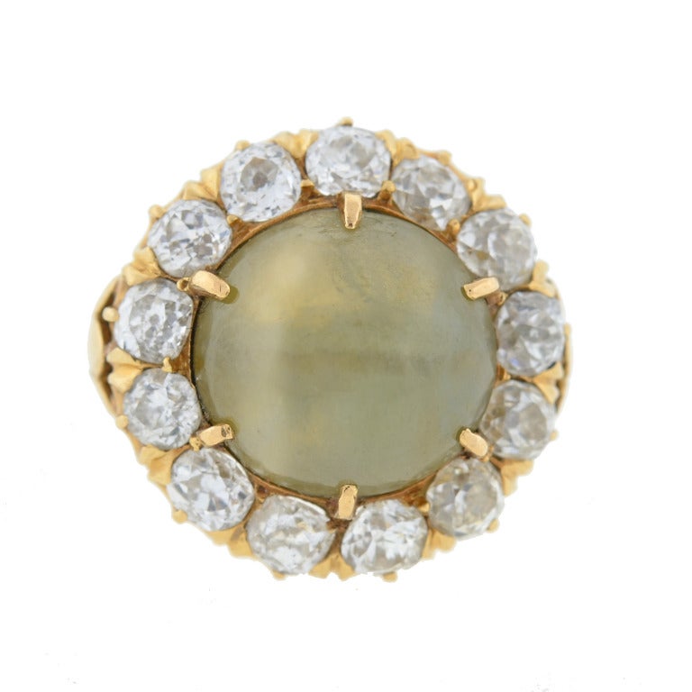 An outstanding chrysoberyl ring from the Victorian (ca1880) era! Made of 14kt yellow gold, the piece holds a large cat's eye chrysoberyl stone at the center, surrounded by a glittering diamond border. The chrysoberyl, which weighs 5+ carats and
