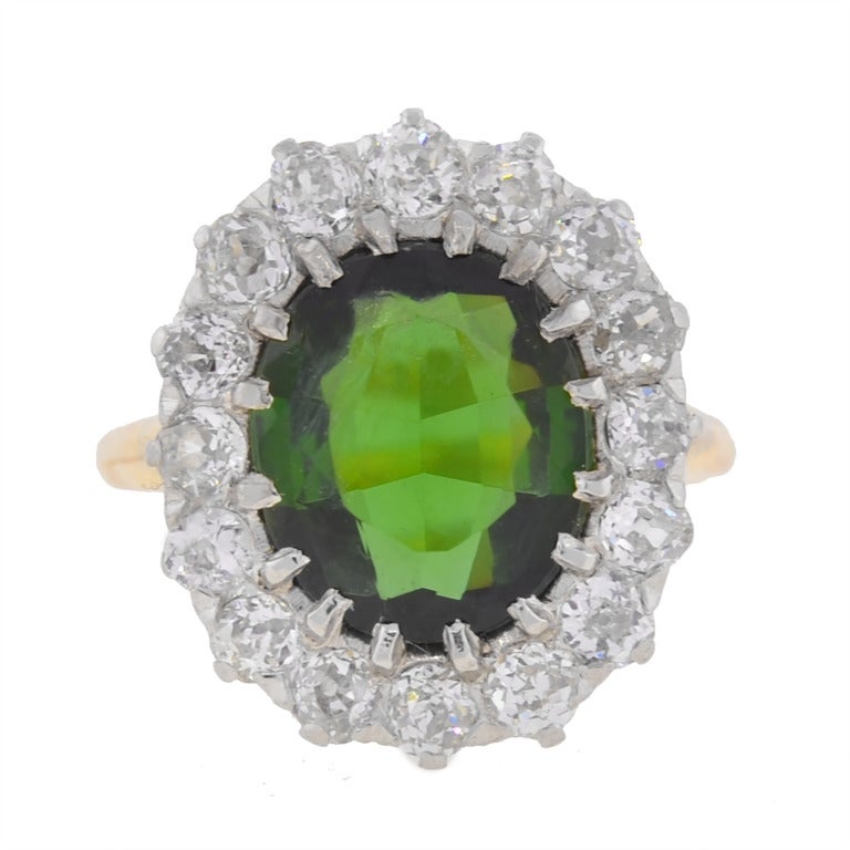 A stunning and unusual tourmaline and diamond ring from the Edwardian (ca1910) era! This fabulous piece is made of 14kt yellow gold and platinum and adorns a round tourmaline stone resting in the center of a diamond frame. The tourmaline, which