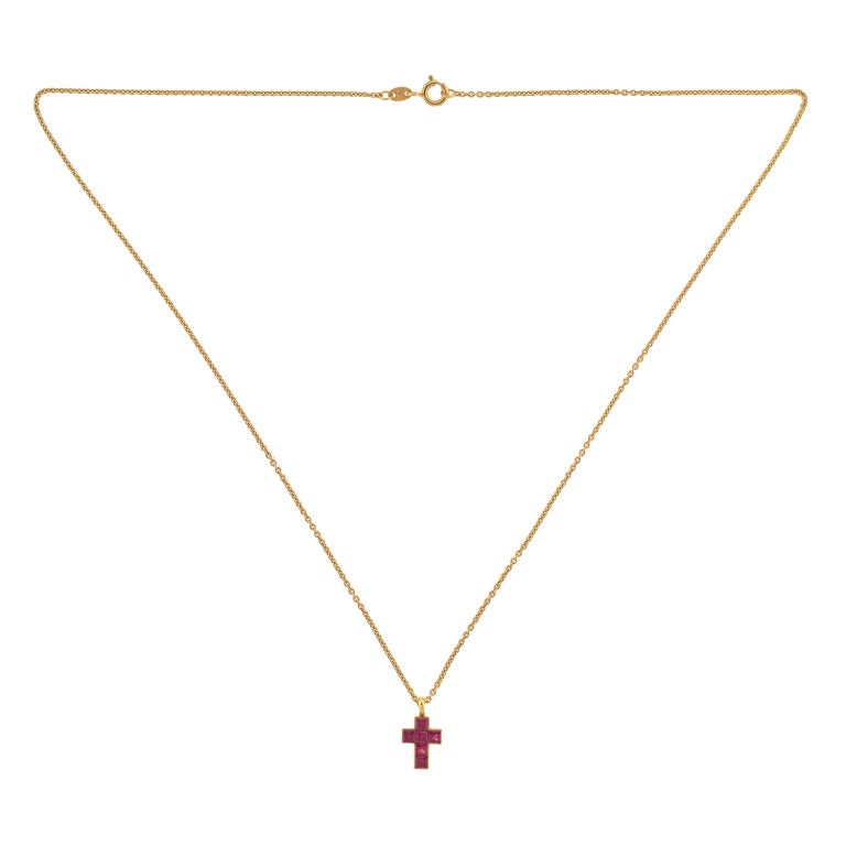 A beautiful Estate cross necklace by legendary maker Cartier! The lovely piece is made of 18kt yellow gold and forms the shape of a delicate cross. The entire front surface of the cross is represented by 6 calibrated rubies, totaling approximately