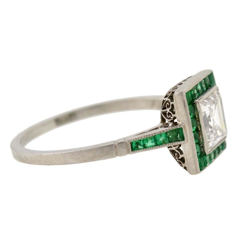 A stunning diamond and emerald ring from the late Art Deco (ca1930) era! This gorgeous ring is made of platinum and has a stunning Square Step Cut diamond bezel set in its center. The diamond weighs approximately 0.85ctw with F color and SI1