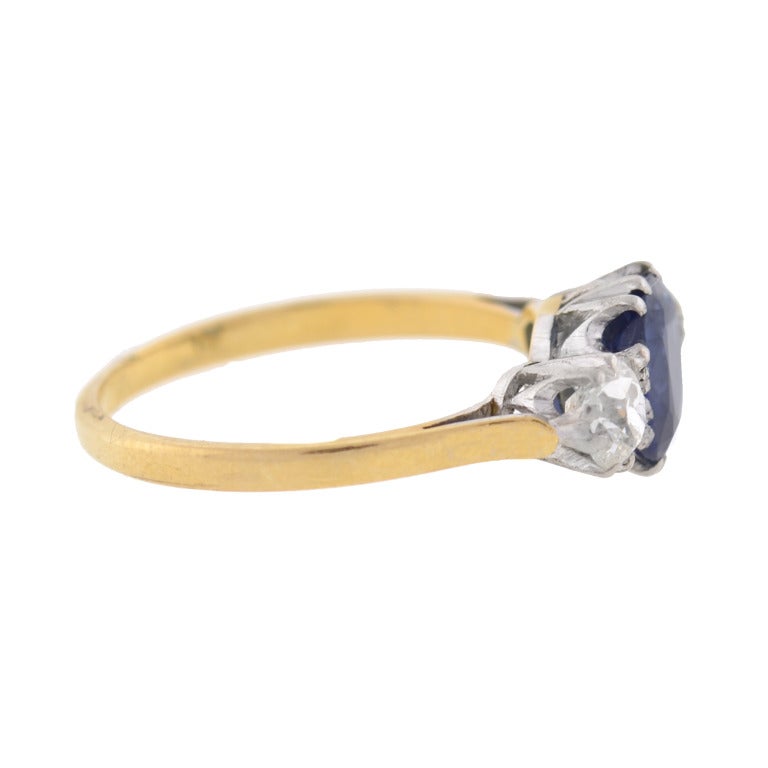 An absolutely exquisite 3-stone diamond and sapphire ring from the Edwardian (ca1910) era! This beautiful piece is made of 18kt yellow gold and adorns a single sapphire stone resting in the center of 2 old Mine Cut diamonds. The center sapphire