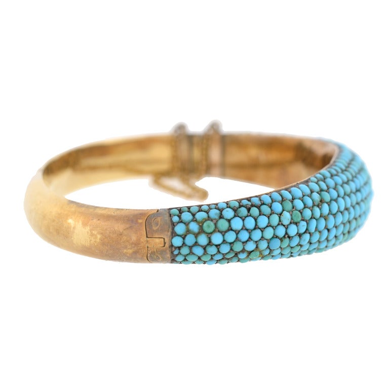 An absolutely gorgeous turquoise bangle bracelet from the Victorian (ca1880) era! This beautiful piece is made of 14kt yellow gold and is detailed with 7 rows of graduating turquoise stones. The pave (French for pavement) set stones vary slightly in
