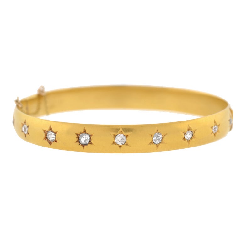 A gorgeous bangle bracelet from the Victorian (ca1900) period! Made of vibrant 18kt yellow gold, this stunning piece holds 10 sparkling old Mine Cut diamonds on its front, each set within a lovely etched starburst design. The diamonds have an