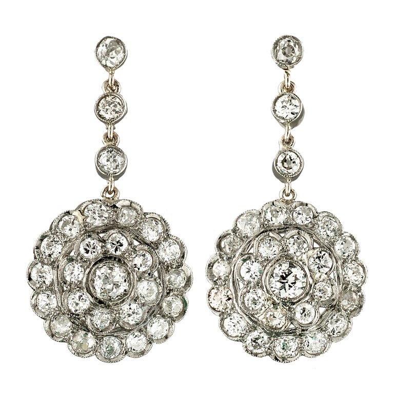 Absolutely exquisite diamond earrings from the late Art Deco (ca1930) era! These gorgeous earrings are made of platinum and adorn a large stacked cluster design which has a flower-like appearance. Each earring has a single diamond that rests in the