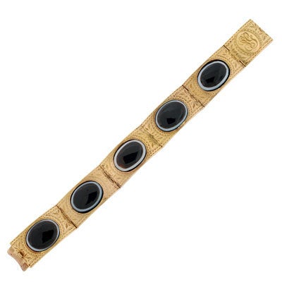 A unique gold and banded agate bangle from the Victorian (ca1880) era! This stunning piece is decorated in a delicate scrolled etched design and five cabochon banded agate stones. The stones are bezel set and rest in between the front face and