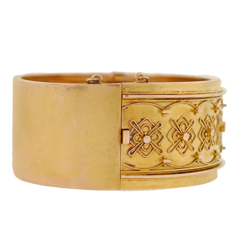 A gorgeous gold bangle bracelet from the Victorian (ca1880) era! This wide bangle is made of vibrant 15kt yellow gold and has a fantastic 3-dimensional design on the front surface. The hinged bracelet has a fine wirework and Etruscan design that