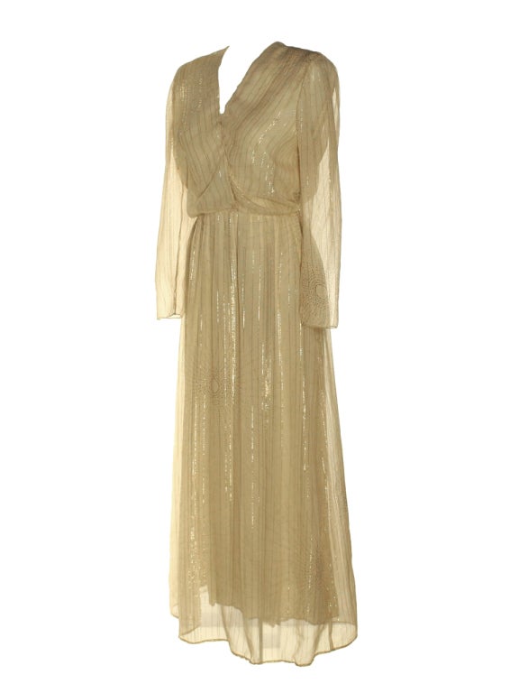 Be the talk of the event in this elegant, cream vintage 1970’s Hanae Mori floor length dress. The light sheer fabric lets you sway through the crowd with grace. The dress slips on with an elasticized waistband, v-neck and long illusion sleeves with