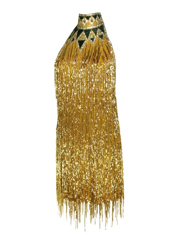 Often called rajah of rhinestones, Bob Mackie makes terrific example of his moniker by creating this outstanding beaded-fringes mini dress. Mackie’s majestic work of art has countless gold beaded-fringes that give a 1920s style to this jewel. Neck