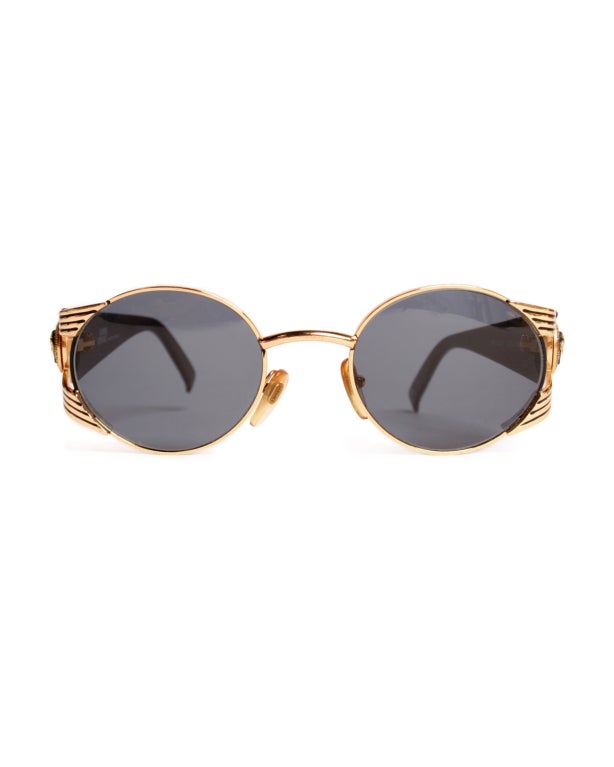 This pair of 1990s Versace round and gold ribbed sunglasses is sure to be a great summer staple.  Adorned with a medusa detail on each side, this pair of Versace sunglasses is sure to add a touch of style to any outfit.

- Frames: 1.25