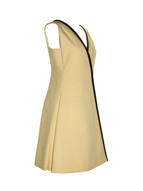 This amazing cream dress was made by Galanos for Amelia Gray in the 1960s. It has a gorgeous black trim and fitted bodice. It features an A-line, wrap style to emphasize the waist, and a V-neckline and back. It has a hidden front closure with a pair