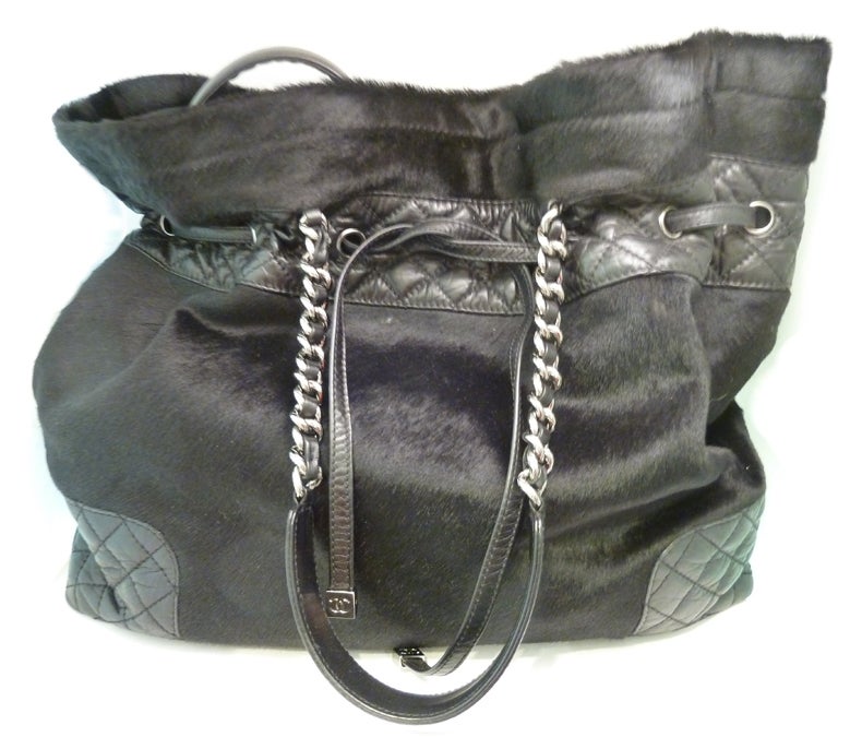 A unique hand-bag from Chanel featuring black pony hair accented with soft Italian quilted leather.  This purse measures 15” x 5 ¼” x 12” with front leather pull and two link & leather straps.   This purse has an inside zipper pocket, is signed