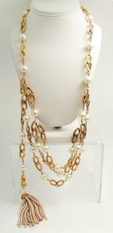 This vintage signed Chanel necklace/belt features faux pearls along a Chanel gold-tone chain.  This piece has 3 front strands with faux white pearls leading to the single strand, which wraps around and ends with a multi-strand tassel of champagne