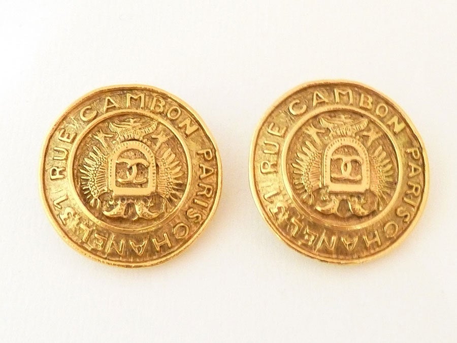 These vintage signed Chanel earrings feature the Chanel address, 31 Rue Cambon, Paris with CC shield in a gold-tone setting.  These clip earrings measure 1 ¼” in diameter.  In excellent condition, these earrings are signed Chanel Made in France.
