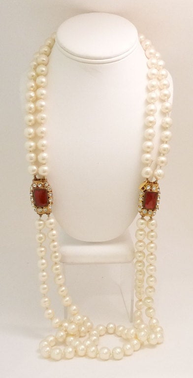 This vintage 1970s Chanel necklace features cranberry Gripoix Glass with clear rhinestone accents and faux pearls in a gold-tone setting.  This stunning  necklace measures 36