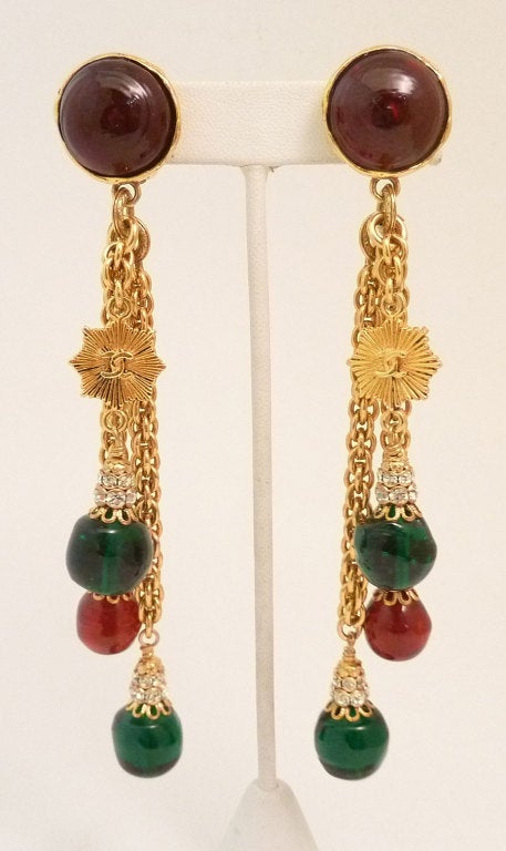 These vintage signed Chanel earrings feature red and green Gripoix glass with a goldtone CC logo and clear rhinestone accents in a gold-tone setting.  In excellent condition, these clip earrings measure 5 ¼? x apx 1? and signed Chanel 97P Made in