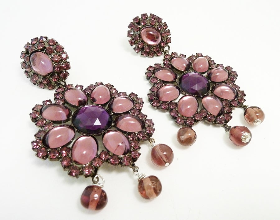These magnificent signed Lawrence Vrba earrings feature amethyst color glass stones in a japanned setting. These clip earrings measure 4 1/8” x 1 ¼”, are signed Lawrence Vrba and are in excellent condition.